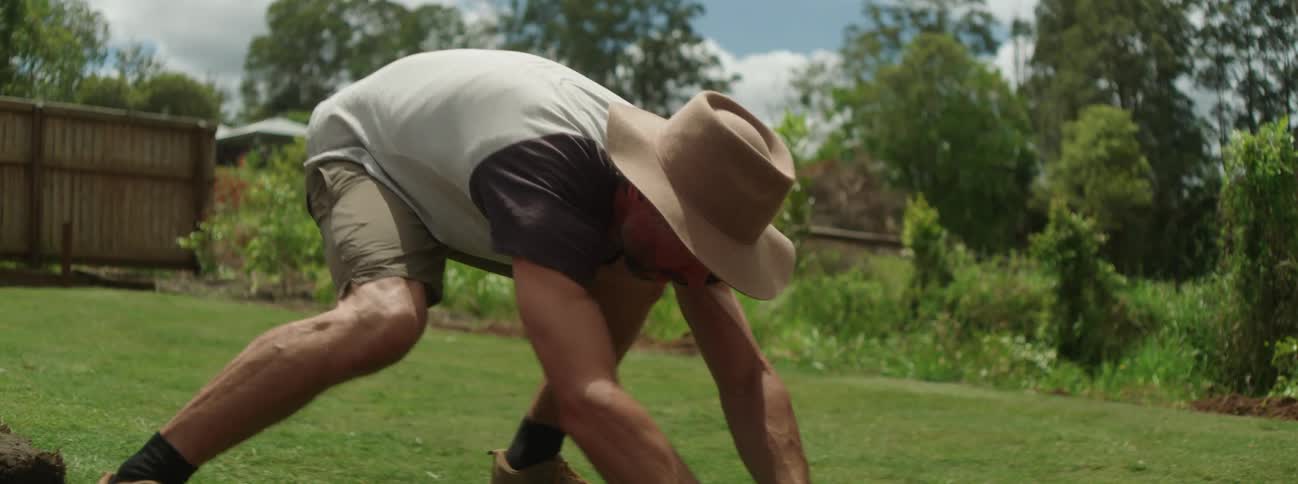 Man lays down sod in yard on a cloudy day