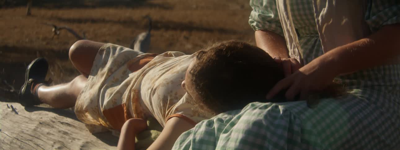 Woman strokes the hair of another woman lying with her head in her lap