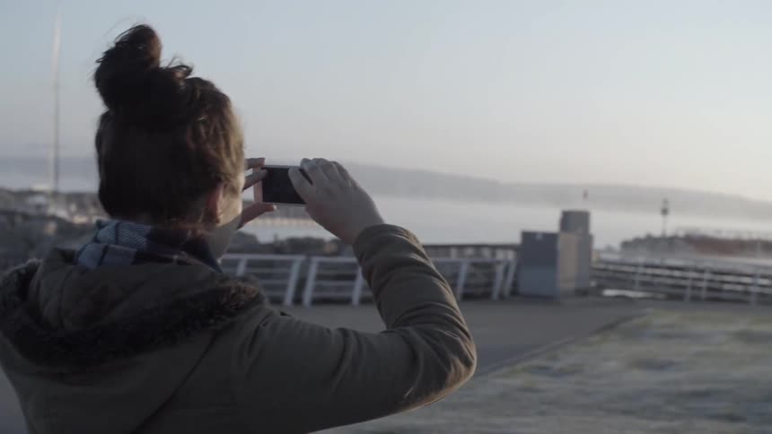 A woman takes pictures on a dock