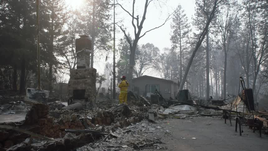 Firefighter stands on post fire debris