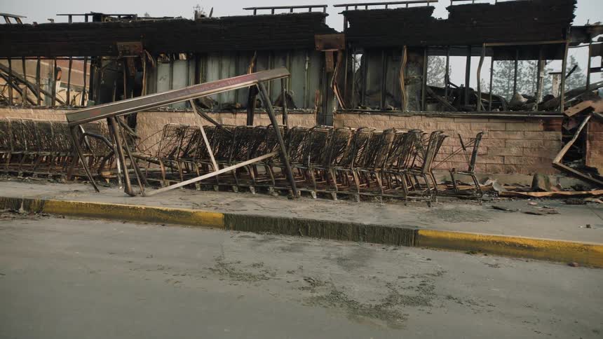 A sidewalk in front of a rundown building with old shopping carts and debris everywhere