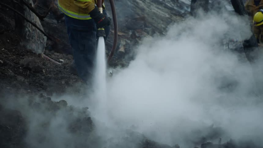 Firefighters work in burnt area of wilderness