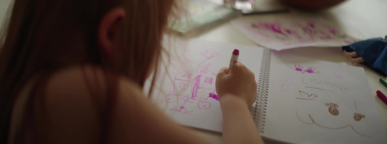Red haired girl sketches at table with marker