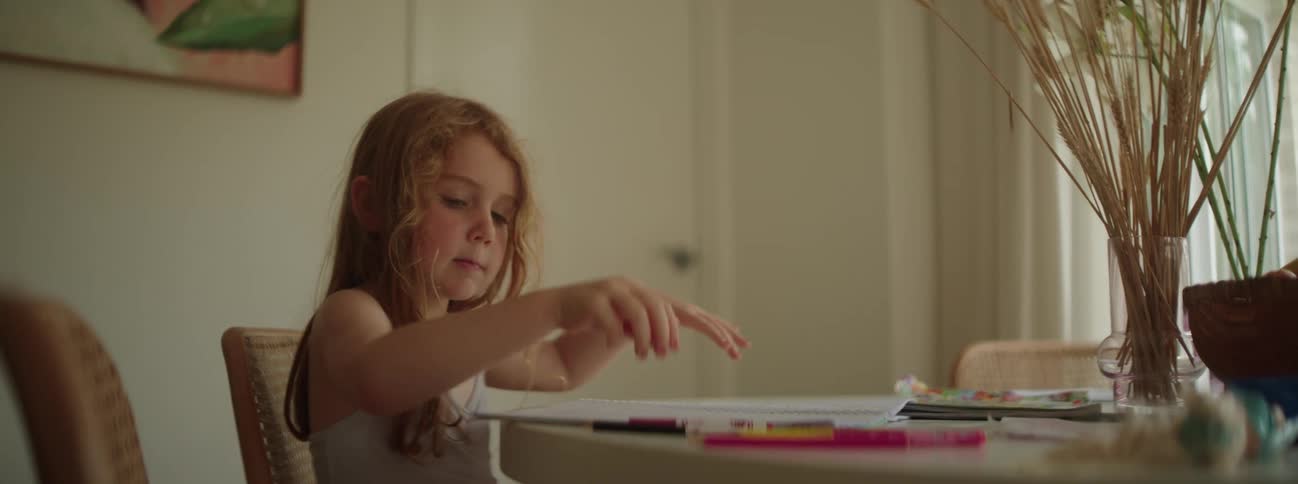 A child reading and coloring in a book at a table