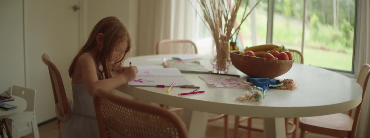 A little girl sits at the table coloring