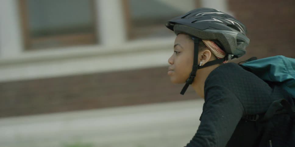 A woman wearing a bike helmet riding her bike