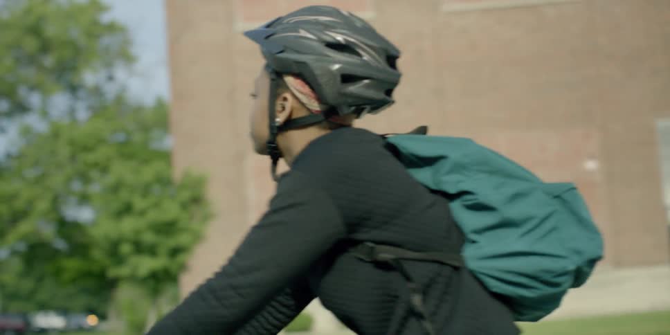 A woman wearing a bike helmet rides her bike on a sunny day