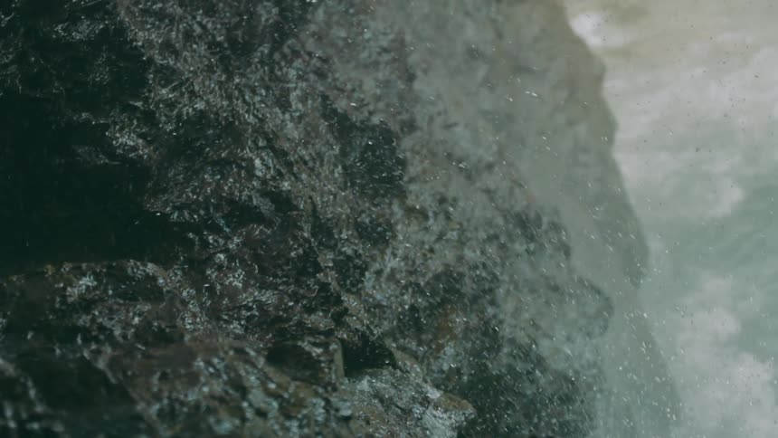 Water is flowing down rocks and splashing into the air and there is a stream below