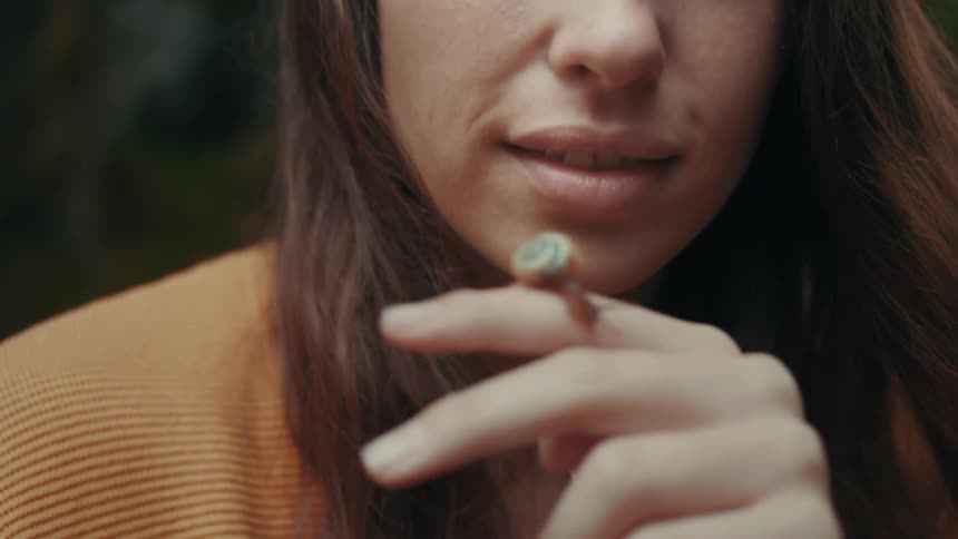 A woman looks at a snail resting on her finger outdoors during the day