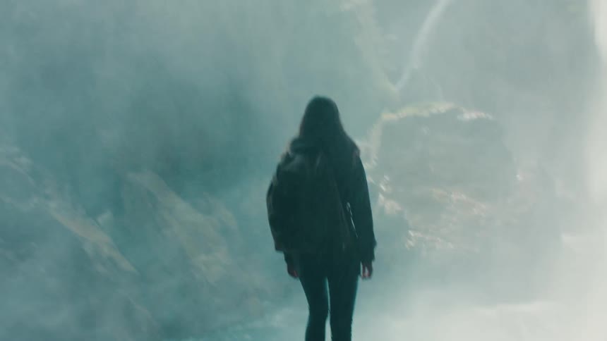 A female watching a waterfall outdoors
