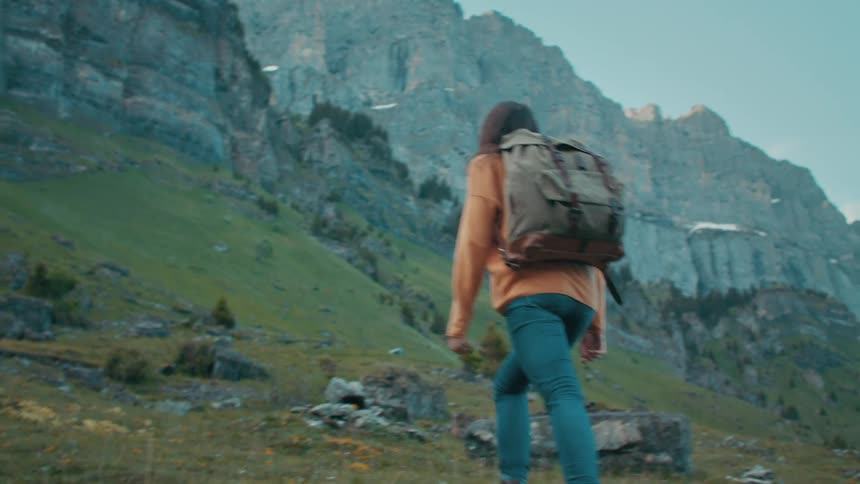 A woman hikes up the side of a mountain and stops to take in the view