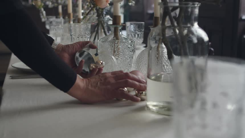 A woman decorates a table at home with christmas ornaments