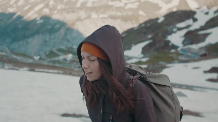 A woman with a backpack is hiking up a snowy mountain