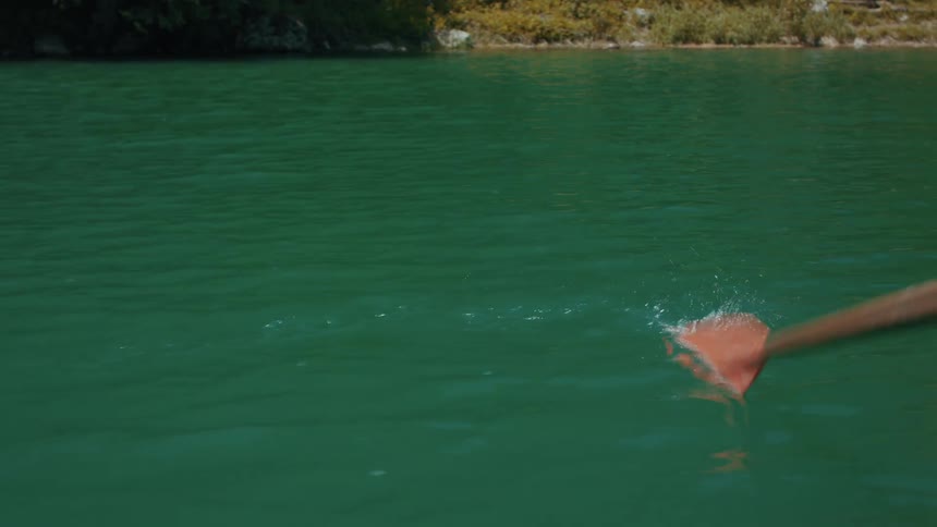 Boat oar moves through green water