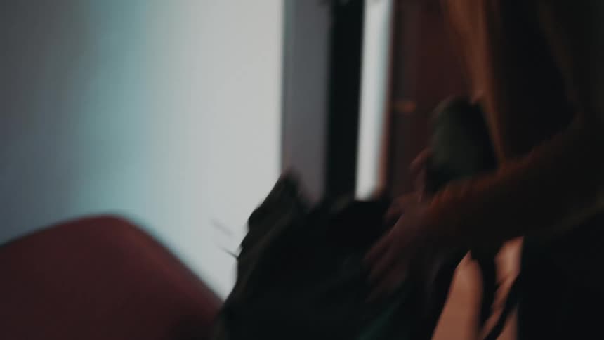 A woman puts things into her bag at home