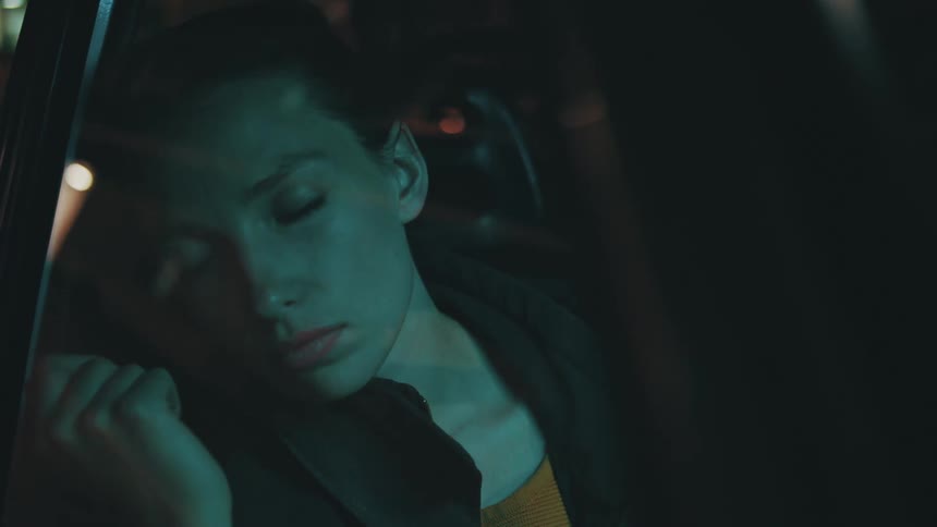 A sad female riding in a vehicle at night