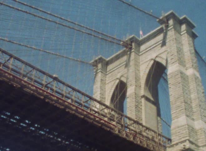 Sunlight shines upon an arch structure on a suspension bridge
