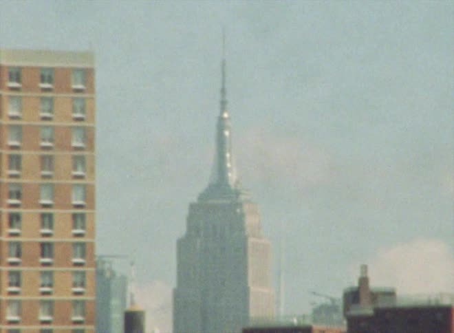 A zoomed in view of a tall building in the city among other buildings