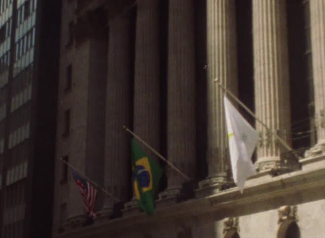 Flags flutter in front of government building at base of columns
