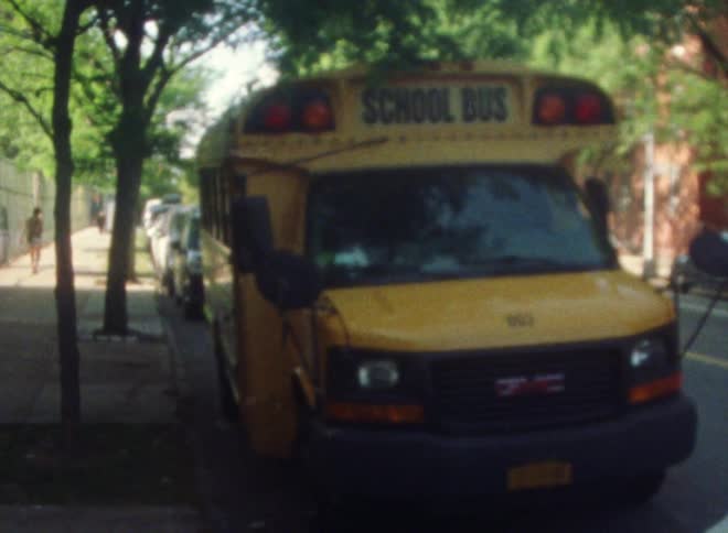 A school bus is stopped near a sidewalk as traffic passes on the street