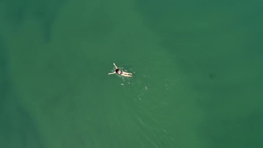 Aerial view of woman in bikini swimming in water