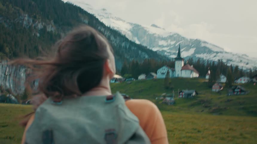 A woman is hiking towards the small town