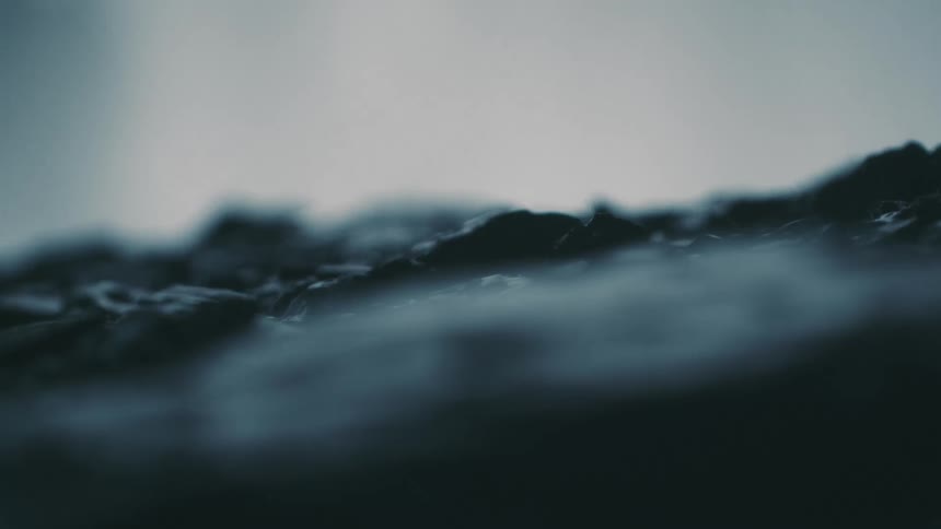 A rocky surface next to a waterfall is covered in moisture