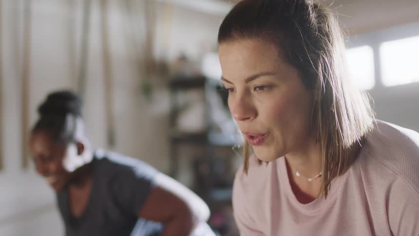 Women with brown and dark hair pink and dark blue shirt lean over and work out in room