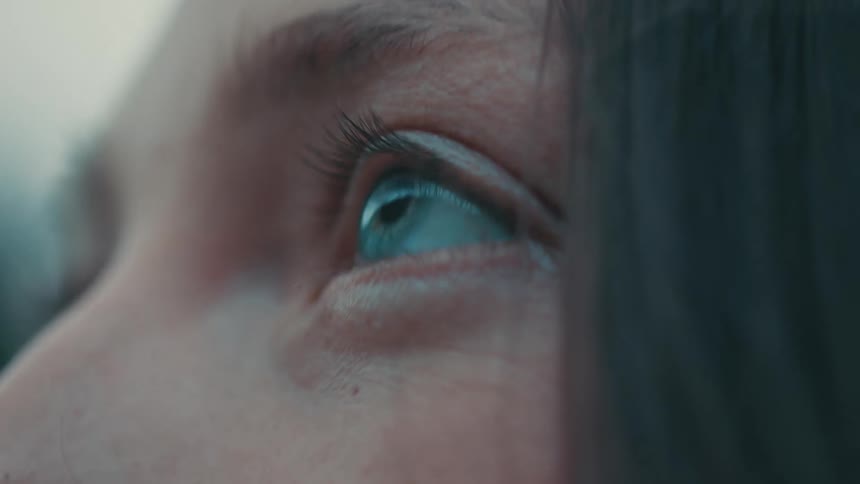 A woman looks up while standing outside