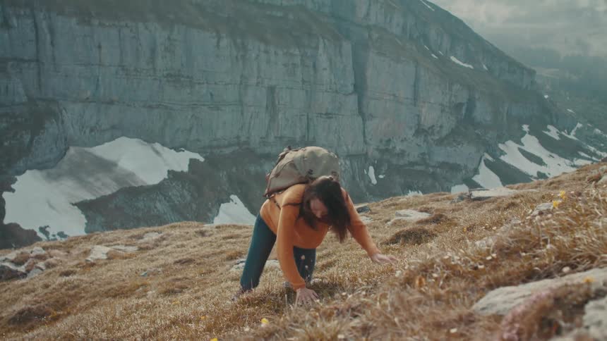 A woman climbs up the steep mountain