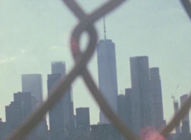 A view of skyscrapers and multiple buildings threw a chain linked fence