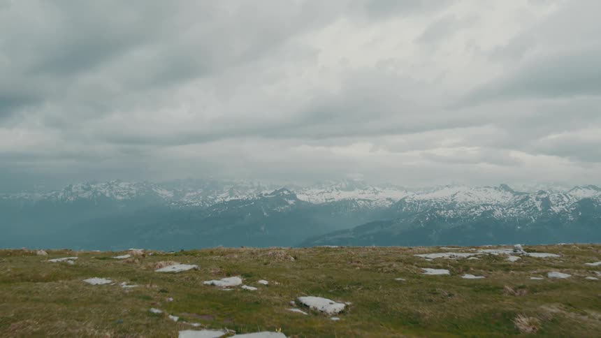 A backpacker hikes toward the edge of a cliff overlooking a mountain range