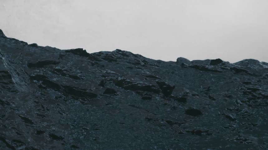 Rain falls hard on a rocky mountain as the wind blows the clouds across the sky