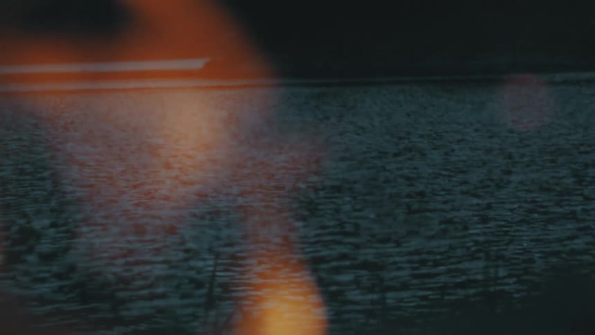Fire sends flames into air that filter view of river and opposite bank at night