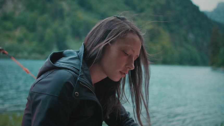 A teenage girl sits on the shore