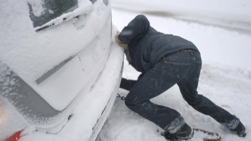 Man puts chains on car stuck in snowy ditch