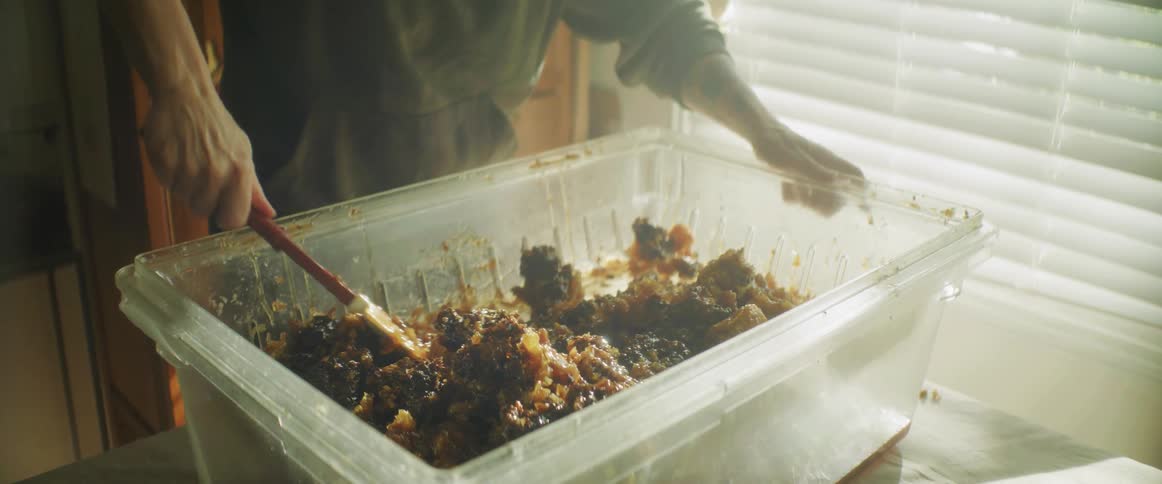 Beekeeper renders wax on table next to window blinds
