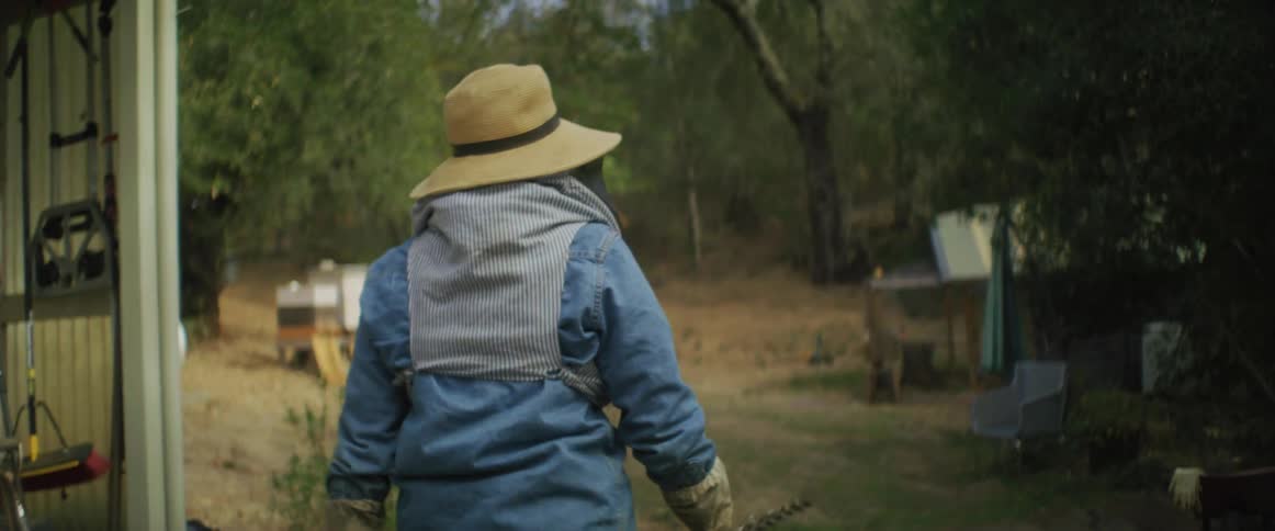 Female beekeeper with protective clothing walks in the yard