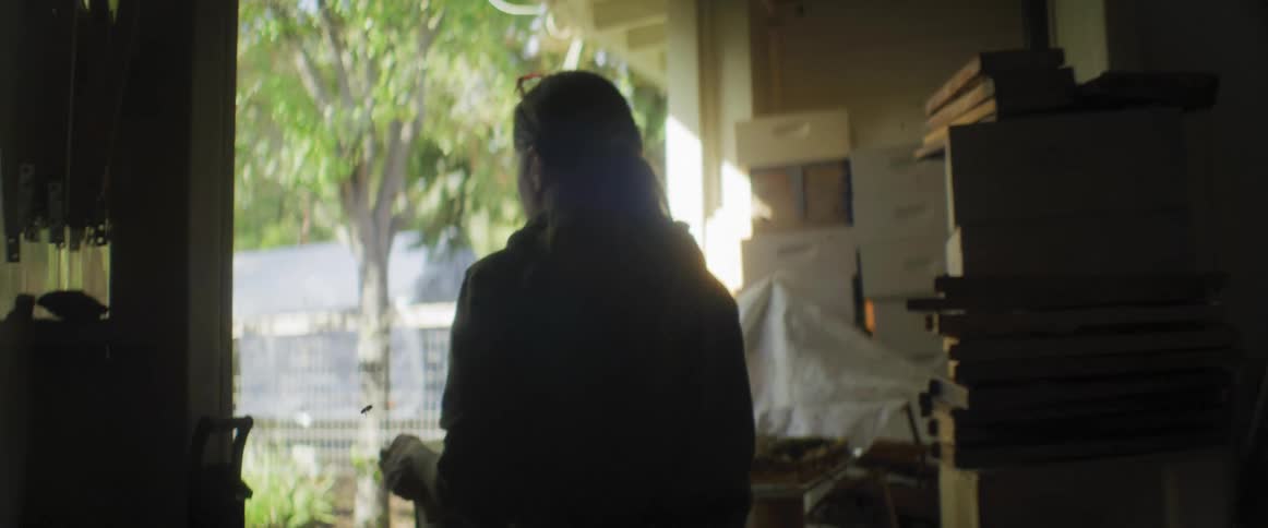 Woman walks to the garden in the backyard through the garage at morning