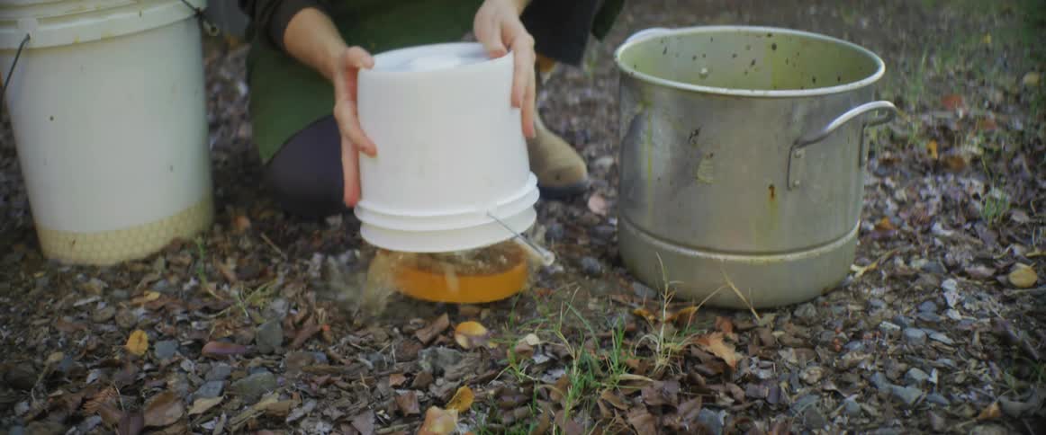 Woman empties plastic buckets in her backyard to clean them
