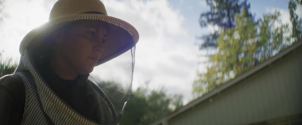 A beekeeper is wearing a beekeeper mask