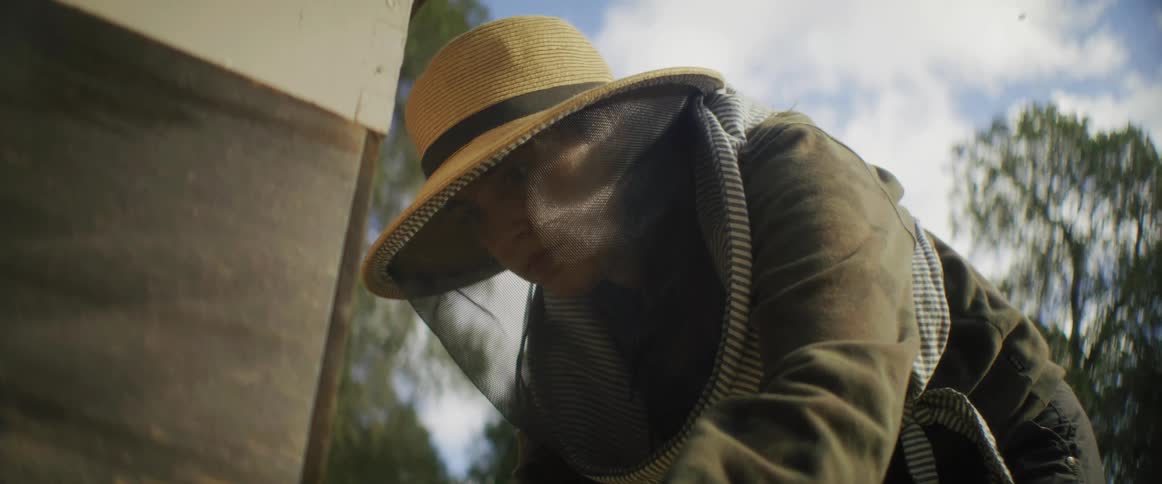Female beekeeper with protective clothing checks box