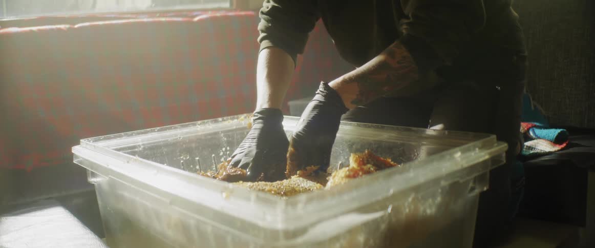 A man mixes up a recipe with his hands in a large tub