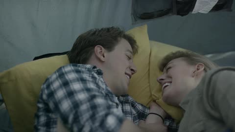 A man and woman lay facing each other and talking
