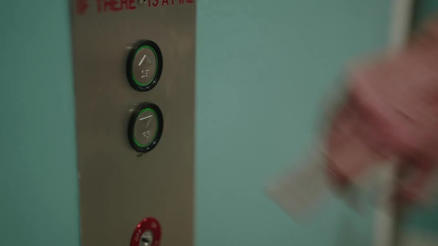 A mans finger presses the button in an elevator