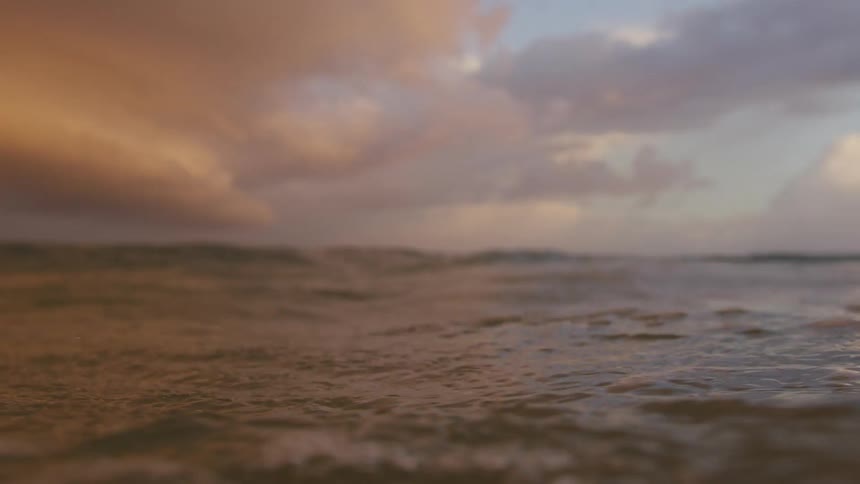 Waves spray water into the air as storm clouds sit on horizon