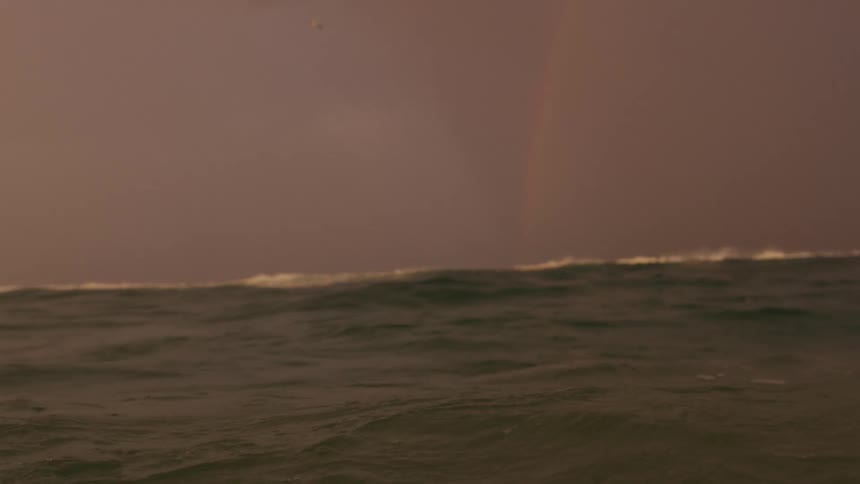 Landscape of body of ocean water and rainbow in the sky