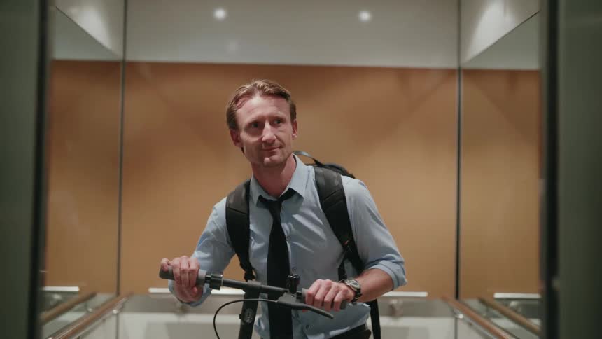 Elevator doors open and a man walks out with his scooter
