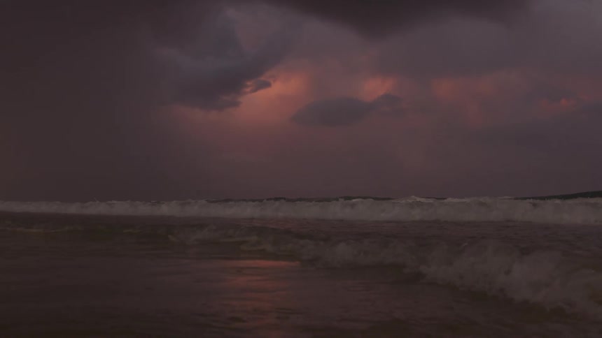 Dark storm clouds over ocean waves rolling in to the shore