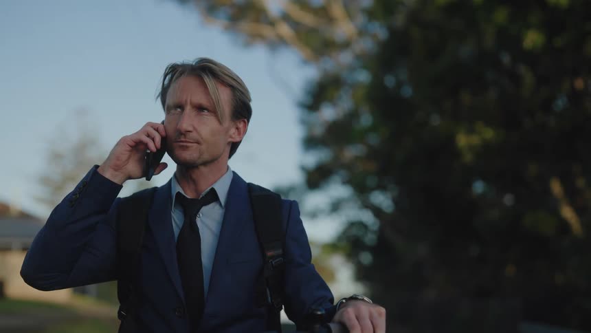 Businessman riding electric scooter stops briefly to take phone call